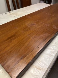 Bouchage, Maquille, Application du vernis au tampon sur les grands panneaux en acajou : cette technique traditionnelle sublime le ramage du bois et sa couleur profonde.