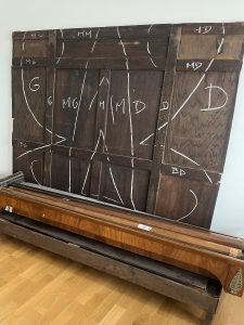 Restauration d'une armoire Empire en placage d'acajou : signes d'établissement, analyse des soulèvements de placage et des manques sur la corniche avant travaux.